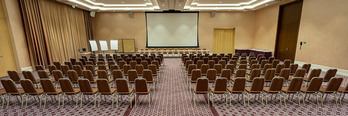 A multi-functional room with rows of seats and a projector screen at the Castanea Forum Center