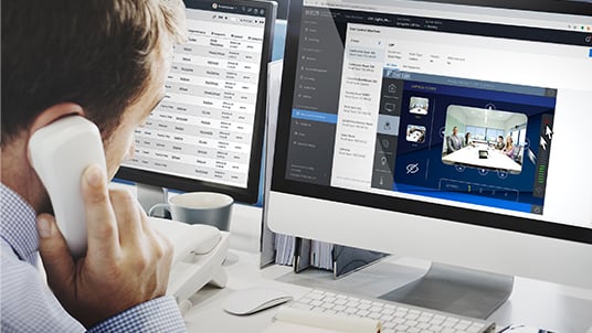 A hepdesk employee remotely assisting a conference call from his desk, while on the phone